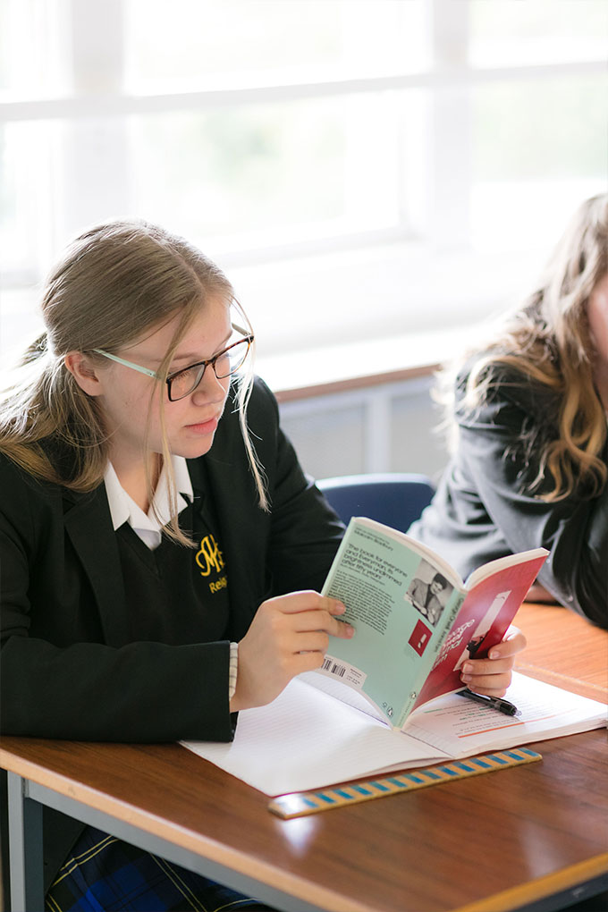 Moon Hall pupil reading a book during a history lesson